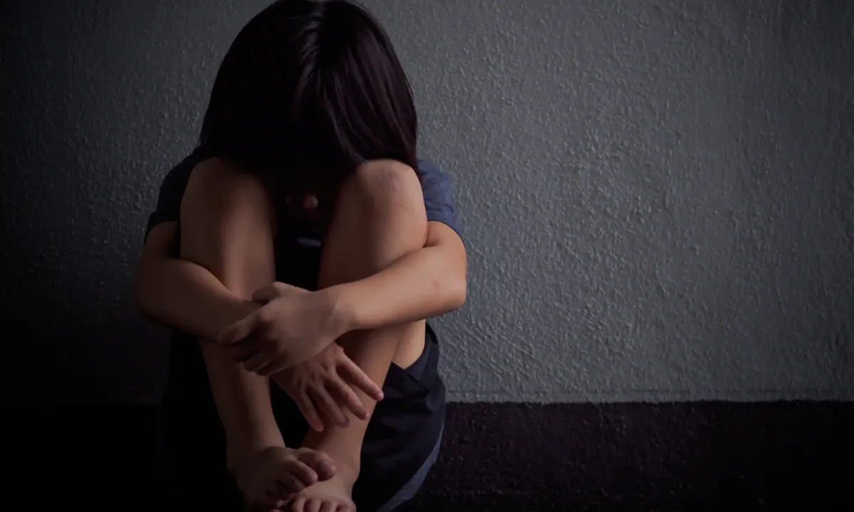 Ängstliches, unsicheres, einsames, trauriges Kind in isolierender, schützender Körperhaltung mit angezogenen Beinen