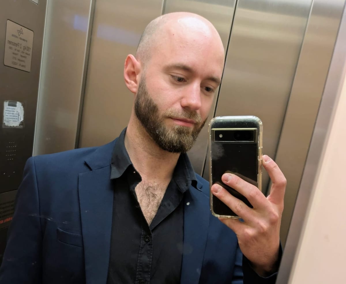 Spiegel-Selfie des Autors im Aufzug: Mann in blauem Sakko und schwarzem Hemd hält ein Smartphone.